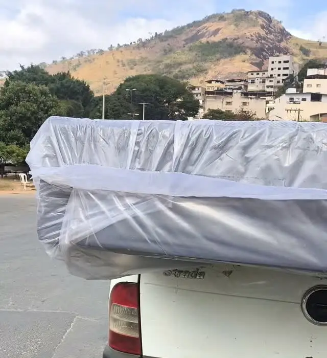 Colchão embalado na caçamba da picape da loja, com o morro de Caratinga ao fundo