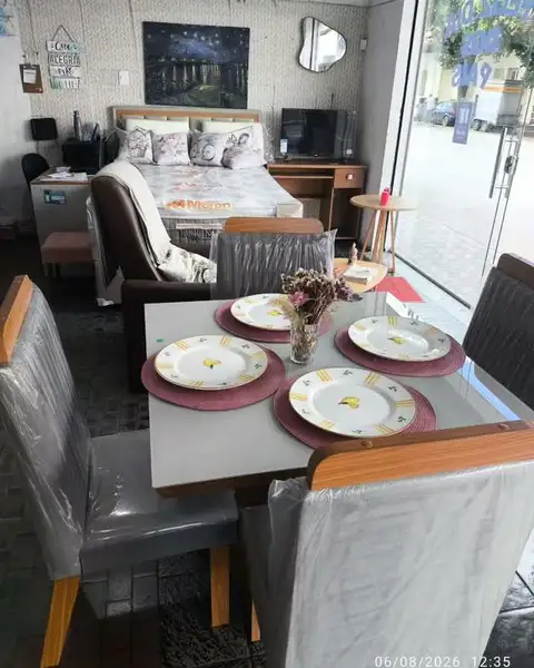 Mesa de jantar posta com cadeiras estofadas, no salão da loja